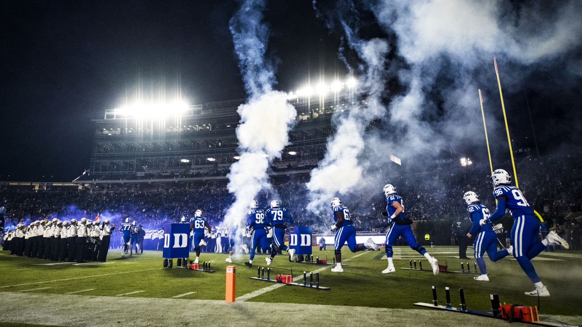 A Group Of People In Blue Uniforms On A Field With A Large Explosion
